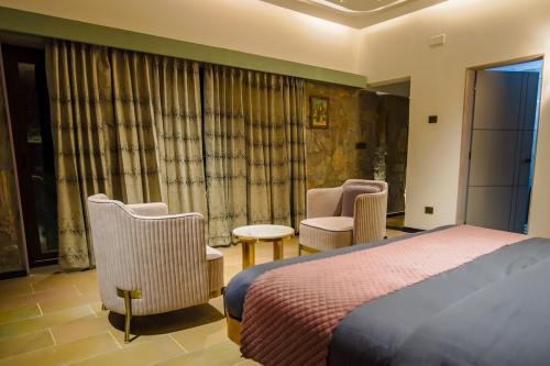 a hotel room with a bed and two chairs at Eraaya Farms Luxury Pet Friendly Villa with Pool in Dabok
