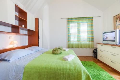 um quarto com uma cama com um cobertor verde e uma televisão em Villa Lora em Tučepi