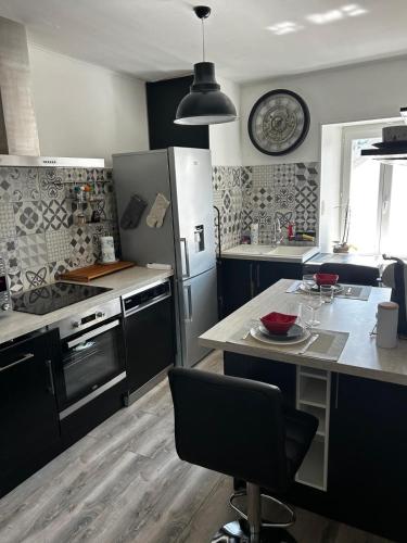 une cuisine avec des armoires noires et une table avec une plaque de cuisson dans l'établissement Le Balcon du Port- private parking, à Aix-les-Bains