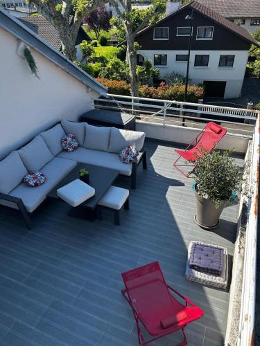 un patio avec un canapé et deux chaises rouges dans l'établissement Le Balcon du Port- private parking, à Aix-les-Bains
