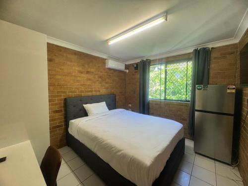 a small bedroom with a bed and a refrigerator at Main Residences Southport in Gold Coast