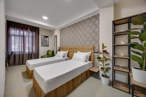 a hotel room with two beds and a plant at Regraph Hotel in Tbilisi City