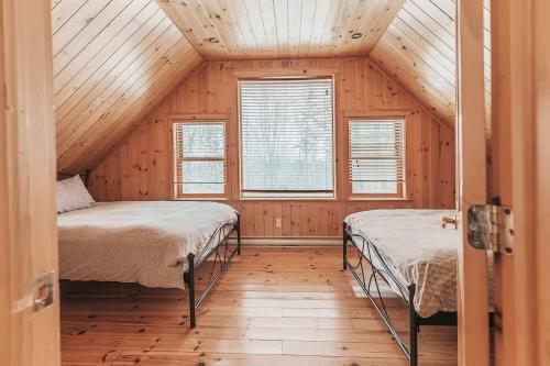 two beds in a room with wooden walls and windows at Ultimate Group Getaway, Private Pool, Spa, Sauna in Mille-Isles