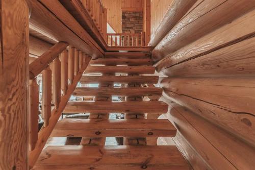 a wooden staircase in a log cabin with wooden floors at Ultimate Group Getaway, Private Pool, Spa, Sauna in Mille-Isles