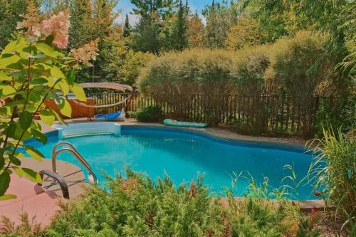 a swimming pool in a garden with a fence at Ultimate Group Getaway, Private Pool, Spa, Sauna in Mille-Isles