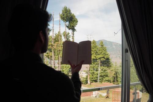 a person reading a book in front of a window at Bhurban Homes in Murree