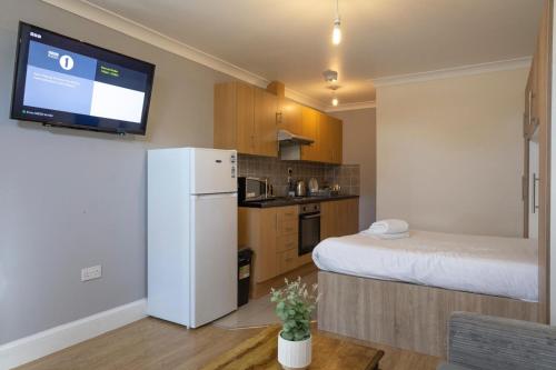 a small kitchen with a white refrigerator and a tv at Kingfisher Court Apartments by UNO in Slough