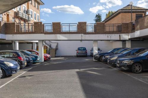 a parking lot with cars parked under a bridge at Kingfisher Court Apartments by UNO in Slough