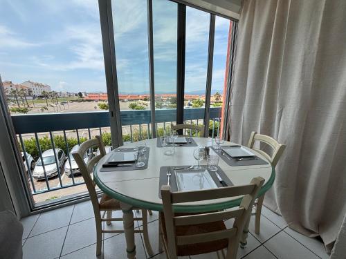 - une table dans une chambre avec une grande fenêtre dans l'établissement L'Ondine - Les pieds dans l'eau - Meublé de tourisme classé 2 étoiles, au Barcarès