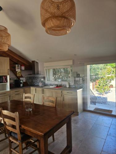 a large kitchen with a wooden table and chairs at Le Rubiz in La Coucourde