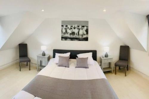 une chambre avec un grand lit et deux chaises dans l'établissement Gite de Coquelicots avec Jacuzzi à Embreville, à Embreville