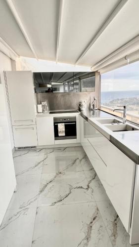 - une cuisine avec des placards blancs et un sol en marbre dans l'établissement Luxury Sea View Penthouse, Monaco Border, 150m2, Parking, à Beausoleil