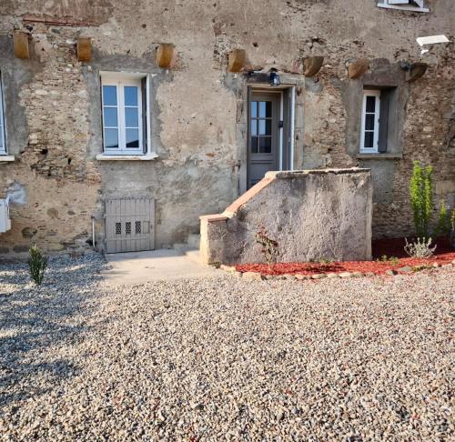 a stone house with a door and a staircase at La Maison de l'Aqueduc in Cournanel