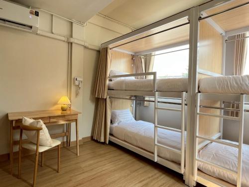 Zimmer mit 2 Etagenbetten, einem Schreibtisch und einem Schreibtisch in der Unterkunft Ease at Sathorn Hostel and Coworking Space in Bangkok