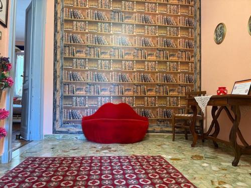 a red chair in a room with a wall of books at FRONTE PO in Turin