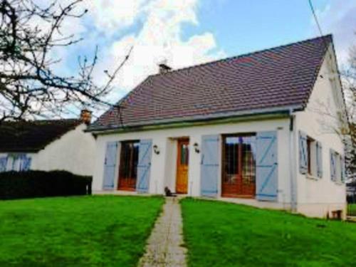 a white house with red doors and a green yard at Gite entre Mer et Vallée à Embreville in Embreville