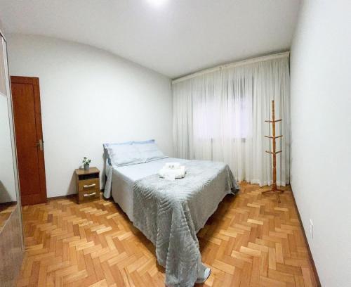 a bedroom with a bed and a wooden floor at Amplo Apartamento no Centro in Nova Friburgo