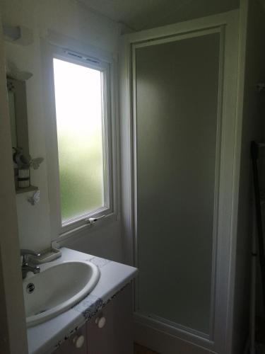 une salle de bain avec un lavabo et une fenêtre dans l'établissement Mobilhome cool, à Pleurtuit