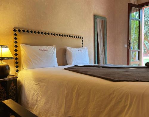 a bedroom with a bed with white sheets and a window at Villa Sophia in Azib Oulad Lâdem
