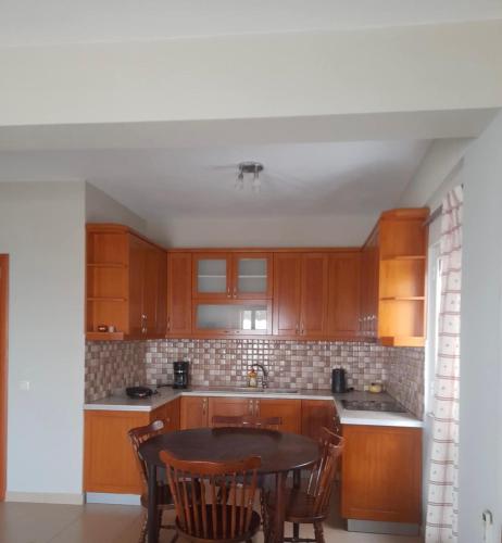 a kitchen with wooden cabinets and a table and chairs at Vila Rapo in Himare