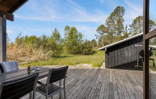 ÅlbækにあるStunning Home In Ålbæk With Saunaの木製デッキ(テーブル、椅子付)