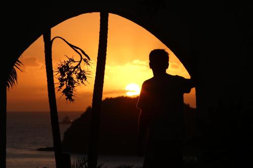 a man standing in front of the sunset at Hostel House 84 in Itajaí