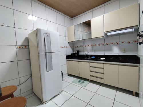 a kitchen with white cabinets and a refrigerator at Cantinho da Rosa in Tibau do Sul