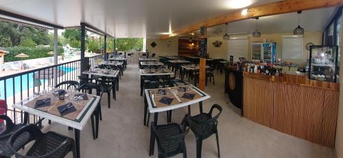 un restaurant avec des tables et des chaises et un bar dans l'établissement Camping Le Chassezac, à Sampzon