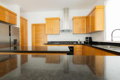 a kitchen with wooden cabinets and black counter tops at Ka' Romana Residences in El Soco