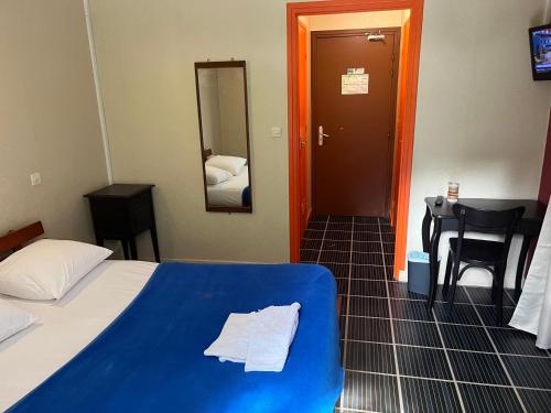 a hotel room with a blue bed and a mirror at Hôtel le belledonne in Le Bourg-dʼOisans