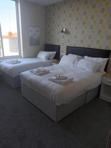 two beds in a hotel room with white sheets at The Saltley Inn in Birmingham