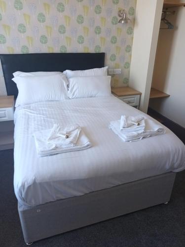 a bed with white sheets and white towels on it at The Saltley Inn in Birmingham