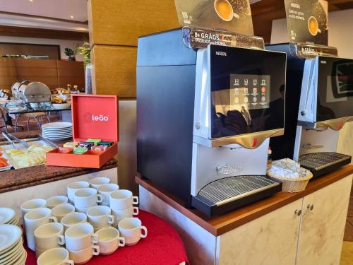 a kitchen with a microwave and cups on a counter at Continental Inn in Foz do Iguaçu