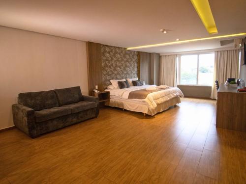 a large bedroom with a bed and a couch at Continental Inn in Foz do Iguaçu