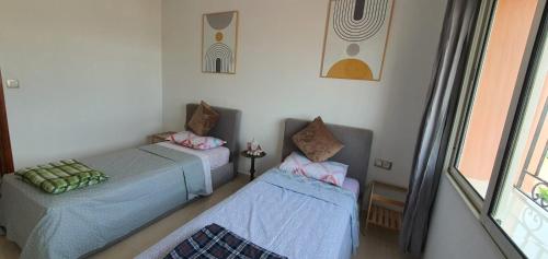 a room with two beds and a window at Duplex La roseraie à 2min de la plage 2 piscines in Sidi Bouzid