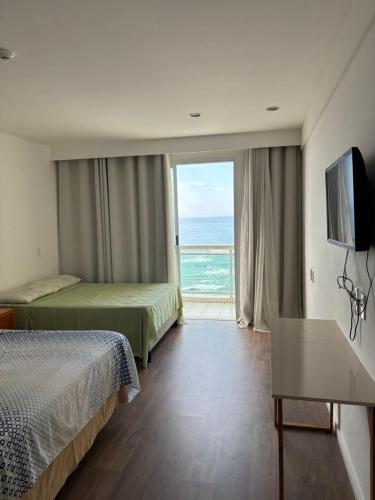 a hotel room with two beds and a view of the ocean at Flat Golden Macaé vista mar in Macaé