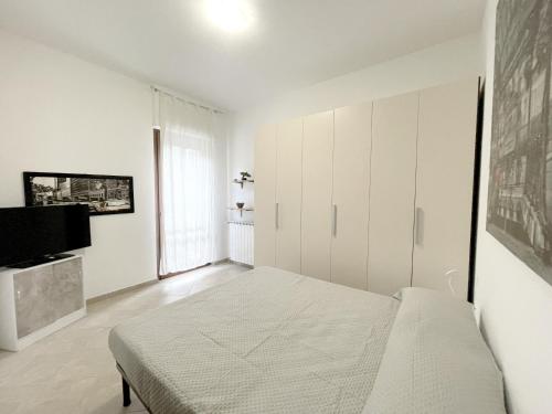 a white bedroom with a bed and a tv at La Colonna 2km dal Centro in Siena