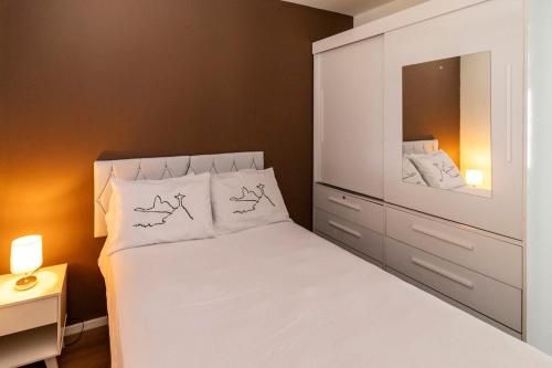 a small bedroom with a white bed and a dresser at Apartamento Carioca in Rio de Janeiro