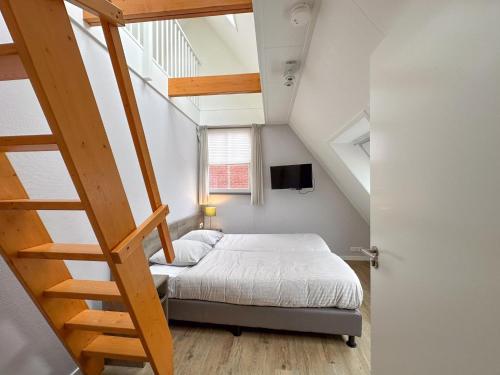 una pequeña habitación con una cama y una escalera en Villa superieur 64, en Colijnsplaat