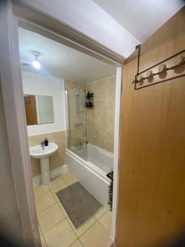 a bathroom with a shower and a tub and a sink at Modern 1-Bed Flat with Balcony in Bradford