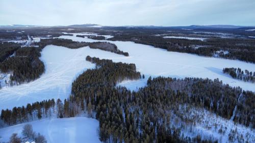 an aerial view of a snow covered field and trees at House Arctic Wolf in Blattniksele