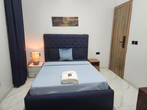 a bedroom with a blue bed with a blue foot board at De- Fmoapartments in Lagos