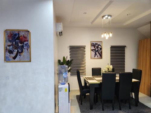 a dining room with a table and black chairs at De- Fmoapartments in Lagos