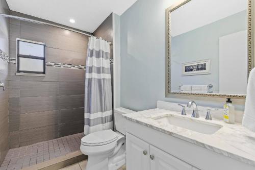 a bathroom with a toilet and a sink and a mirror at Walk to the Beach & Everywhere! Private Pool! in Henry Key