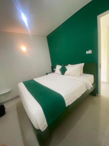 a bedroom with a large bed with a green wall at AI Hotel Kuta - 15 Second to the Beach and 1 Minute to Airport by Micky Studio in Ngurah Rai International Airport