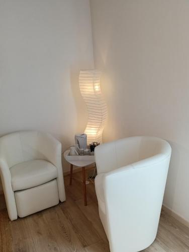 a living room with two white chairs and a table at Les Volets Verts in Saint-Antonin-Noble-Val
