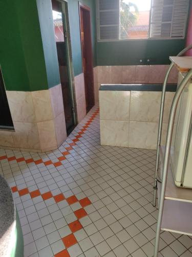 a bathroom with a white tiled floor with orange and green at Motel ritz in Lavras