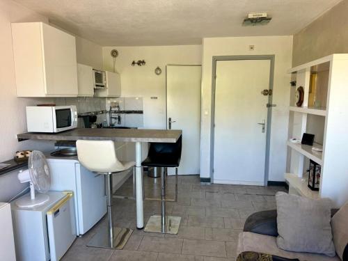 une cuisine avec des armoires blanches et une table et des chaises dans l'établissement Studio idéal couple, au Cap d'Agde