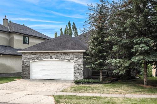 a house with a white garage door in a yard at Cozy bedroom in quiet community in Calgary