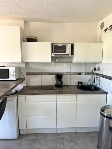 une cuisine avec des armoires blanches et un micro-ondes dans l'établissement Studio idéal couple, au Cap d'Agde